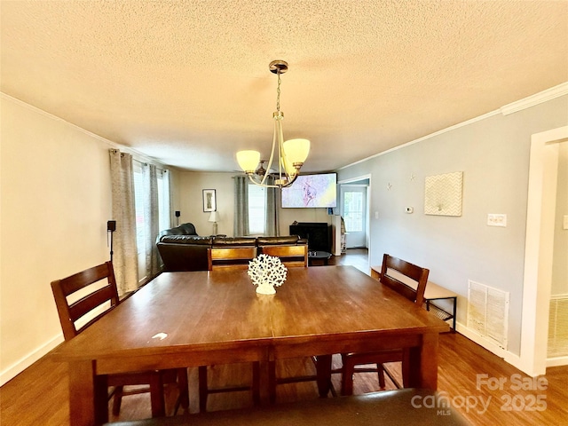 dining space with a notable chandelier, a textured ceiling, and crown molding