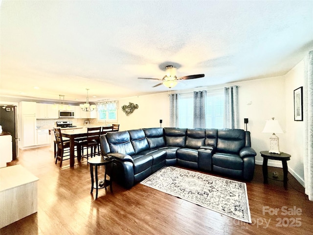 living area with baseboards, a textured ceiling, a ceiling fan, and wood finished floors
