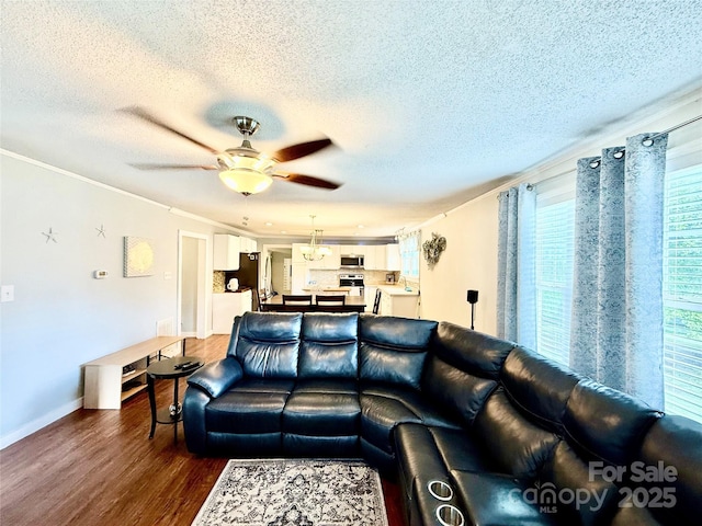 living room featuring baseboards, dark wood-style flooring, a ceiling fan, a textured ceiling, and crown molding