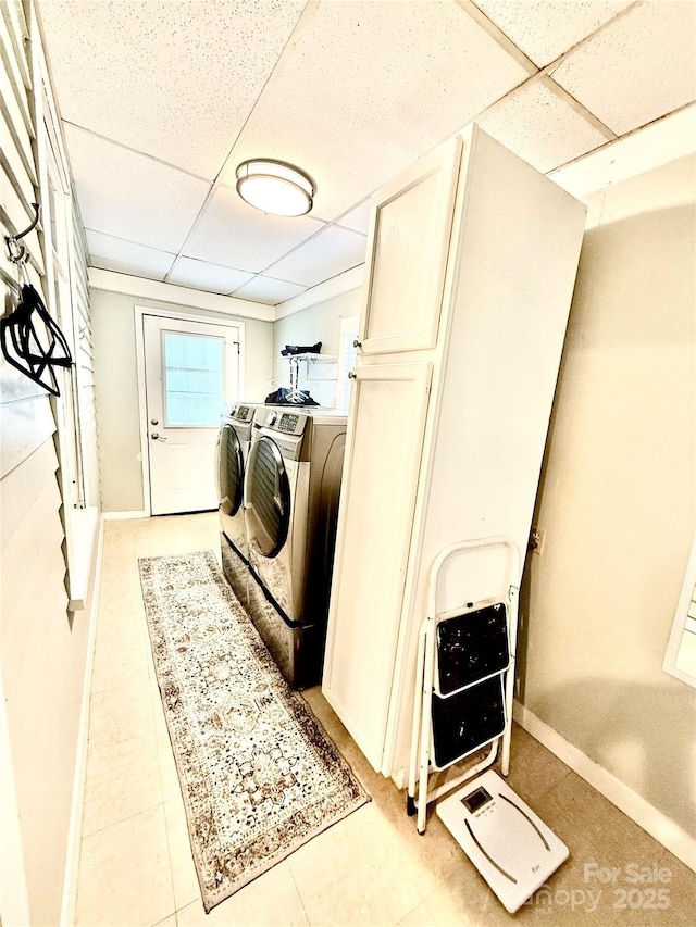 clothes washing area featuring baseboards, separate washer and dryer, and laundry area