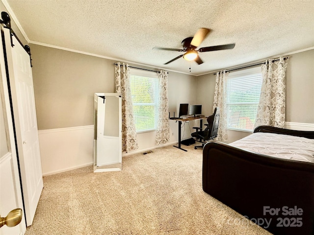bedroom featuring a textured ceiling, baseboards, ornamental molding, and a barn door