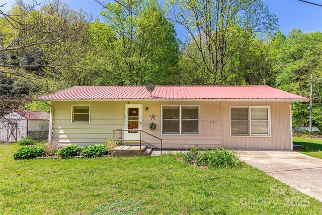 single story home featuring metal roof and a front lawn
