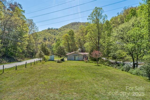 view of yard featuring a view of trees and an outdoor structure