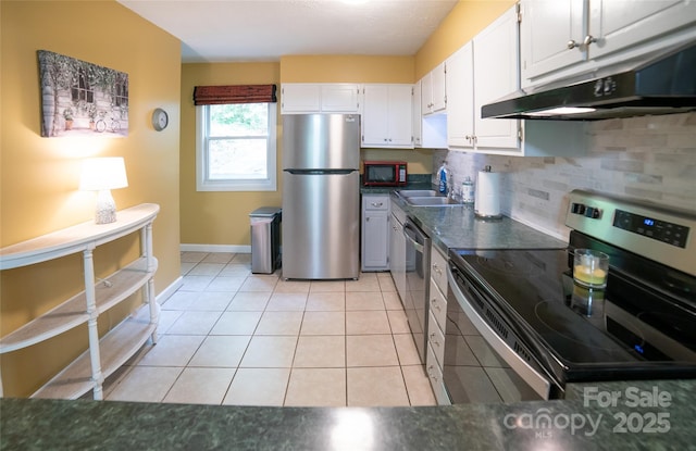 kitchen featuring white cabinetry, dark countertops, appliances with stainless steel finishes, and a sink