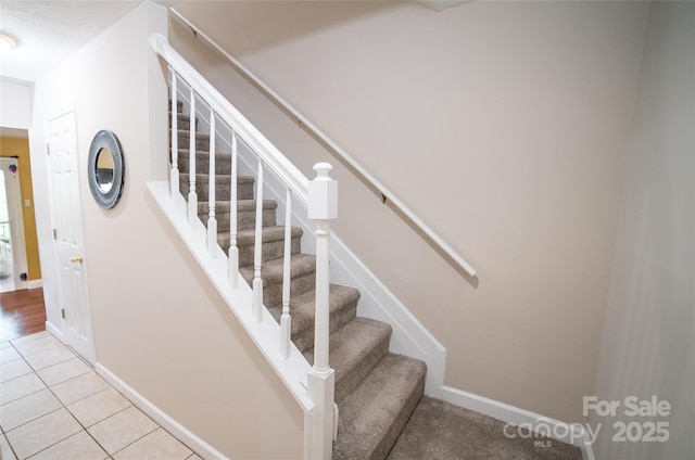 staircase with baseboards and tile patterned floors