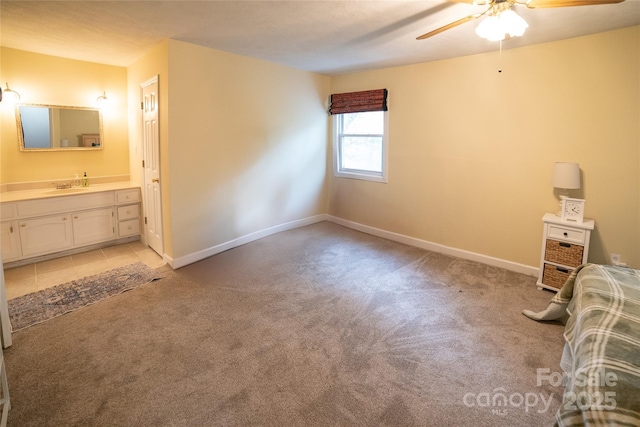 unfurnished bedroom featuring light carpet, a sink, connected bathroom, and baseboards