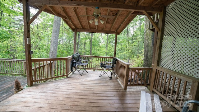 wooden terrace featuring a wooded view and a ceiling fan