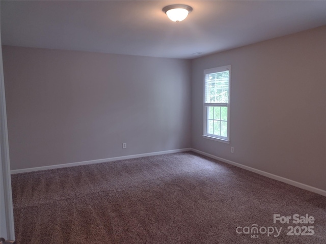 carpeted empty room featuring baseboards