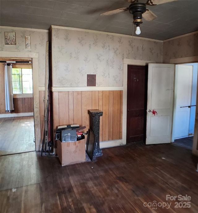 interior space with ceiling fan, wooden walls, a wainscoted wall, and dark wood-style floors