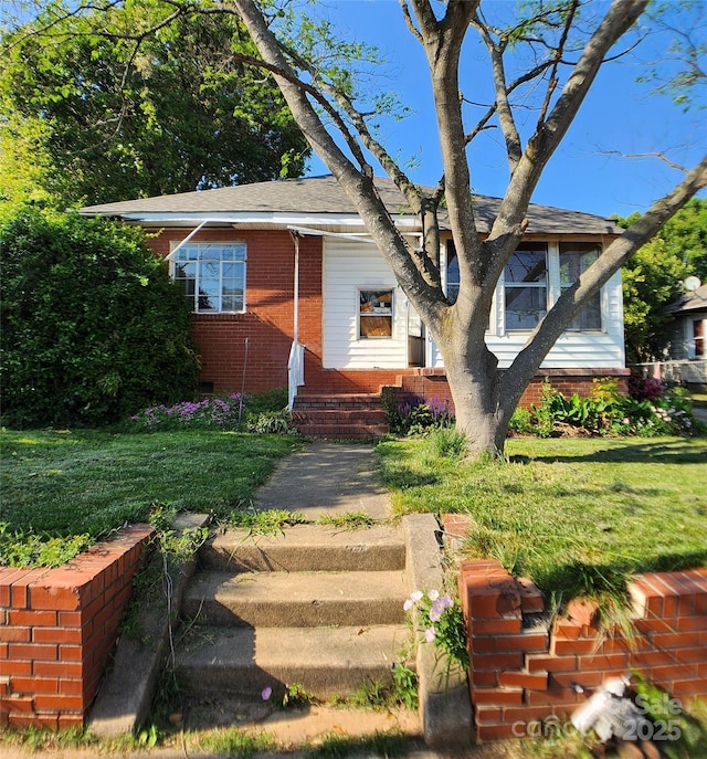 view of front of property featuring a front lawn and brick siding