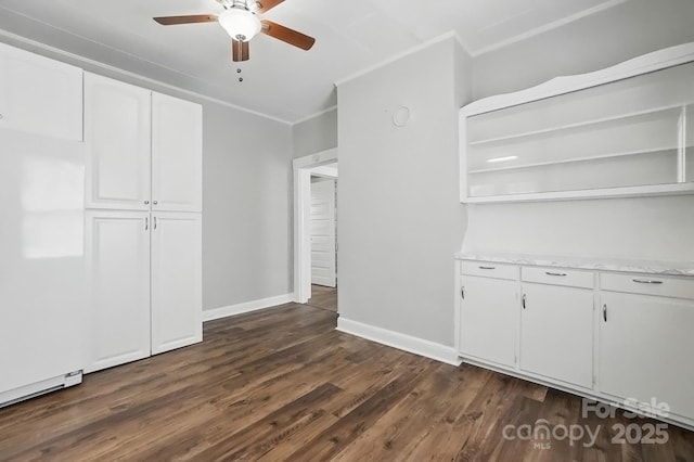 interior space with dark wood-style flooring, ornamental molding, baseboards, and ceiling fan