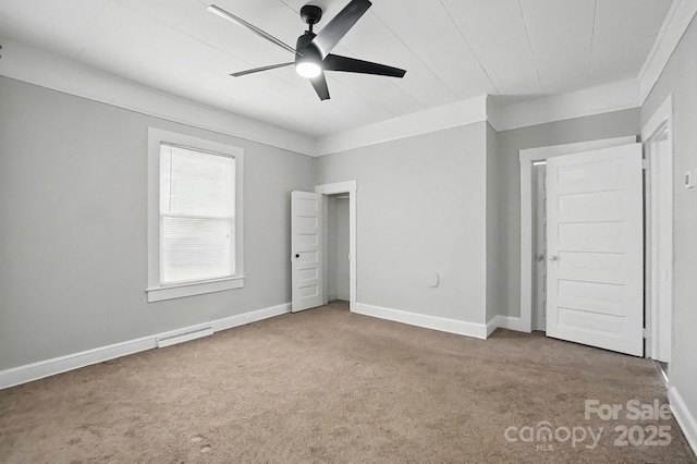 unfurnished bedroom with ornamental molding, carpet flooring, baseboards, and visible vents