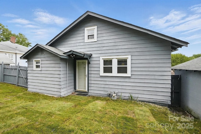 back of house with fence and a lawn