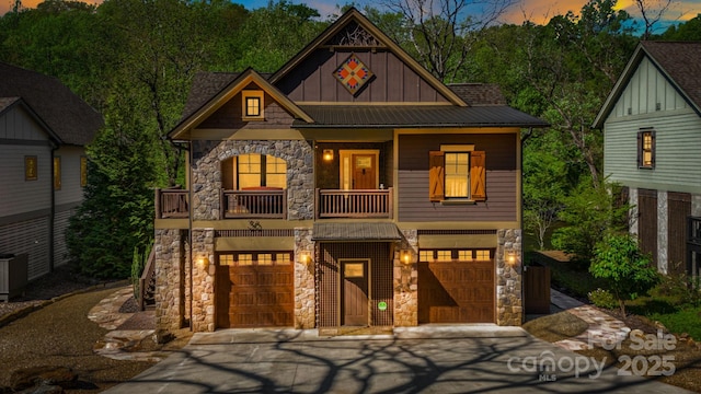 craftsman-style house featuring a balcony, board and batten siding, concrete driveway, and stone siding