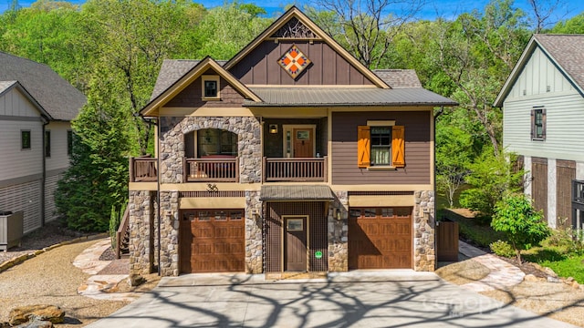 craftsman-style house with board and batten siding, concrete driveway, a balcony, and stone siding