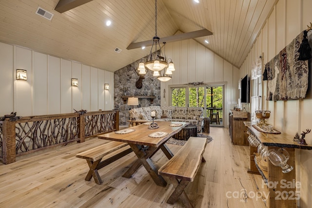 dining room with visible vents, light wood finished floors, a decorative wall, and high vaulted ceiling