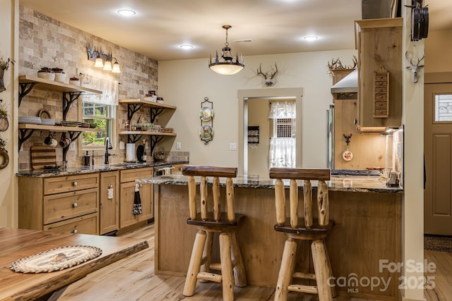 bar with light wood-style floors, recessed lighting, a sink, and decorative light fixtures