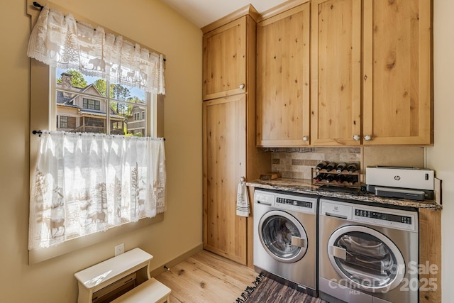 clothes washing area featuring washing machine and clothes dryer, baseboards, and light wood-type flooring