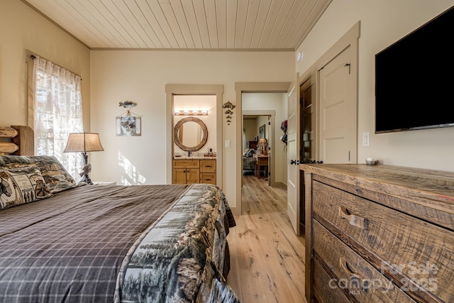 bedroom featuring wood ceiling, ornamental molding, light wood-type flooring, and ensuite bath