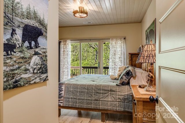 bedroom featuring access to outside, ornamental molding, and wood finished floors