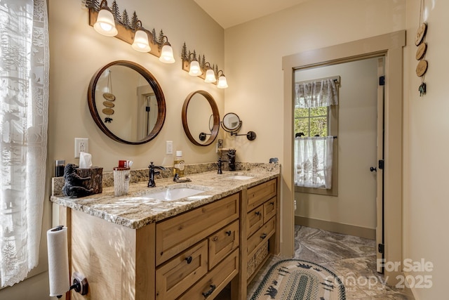 bathroom featuring a sink, baseboards, double vanity, and marble finish floor