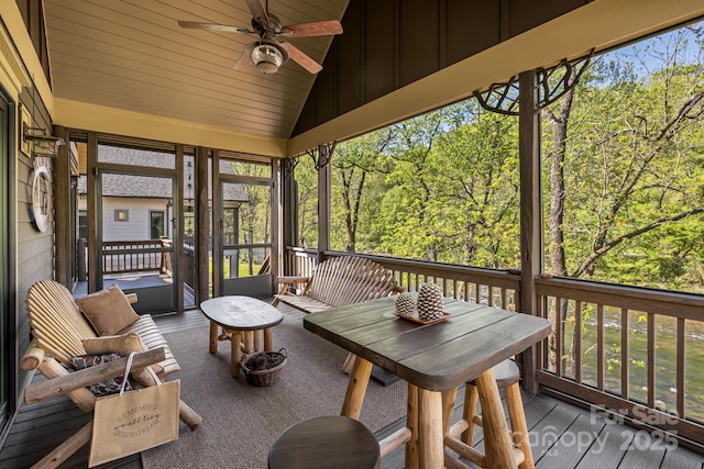 sunroom featuring a ceiling fan and a wooded view