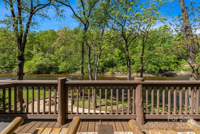 deck with a water view and a wooded view