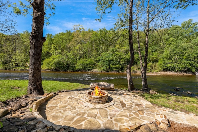 view of patio with a forest view and an outdoor fire pit