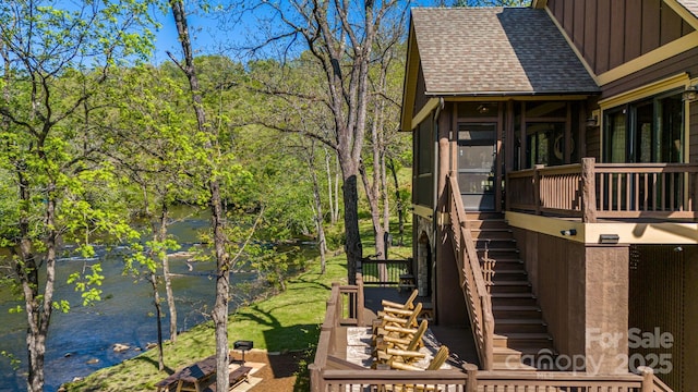 view of side of home with stairway, board and batten siding, and a shingled roof
