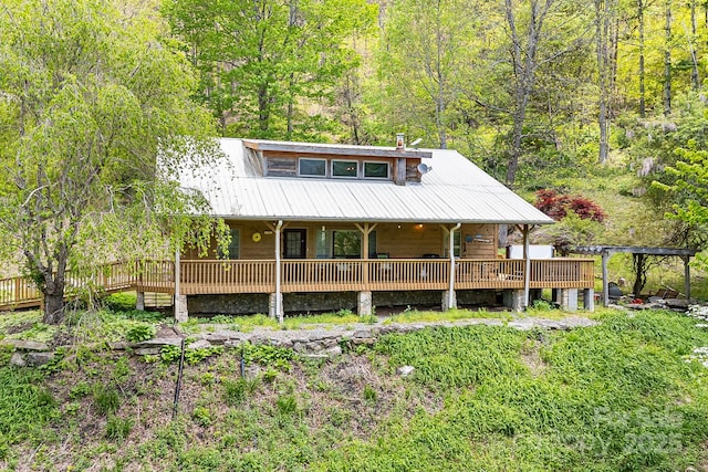 exterior space with covered porch, a wooded view, and metal roof