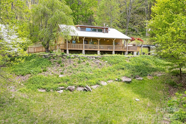 rear view of house featuring a view of trees and covered porch