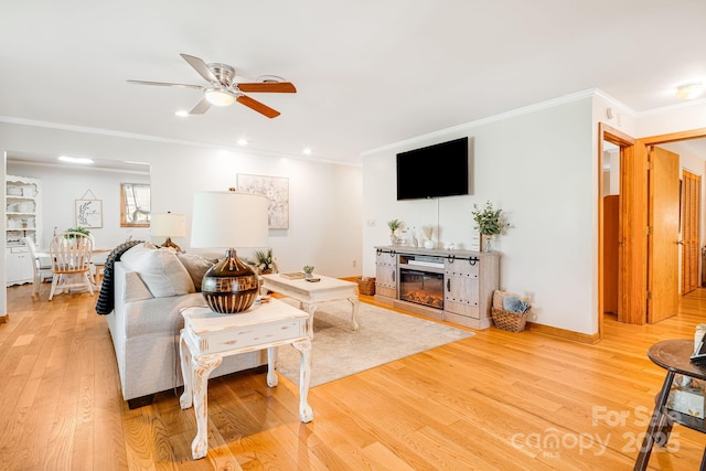 living room with crown molding, a glass covered fireplace, wood finished floors, recessed lighting, and a ceiling fan