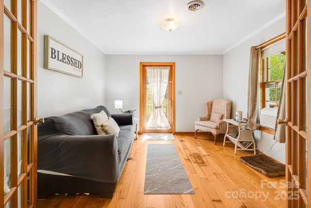 living area with crown molding, baseboards, visible vents, and hardwood / wood-style flooring