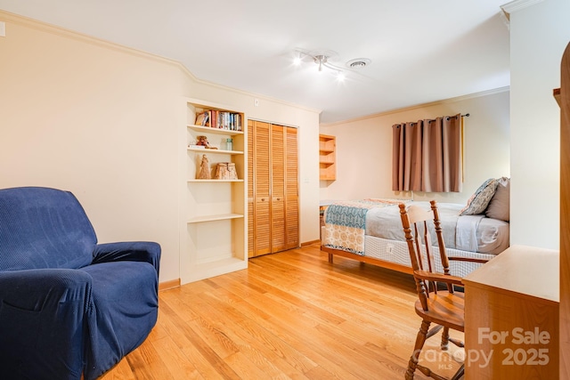 bedroom with a closet, ornamental molding, visible vents, baseboards, and light wood-style flooring