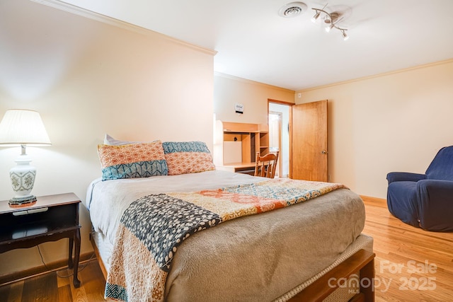bedroom with ornamental molding, light wood-type flooring, and visible vents