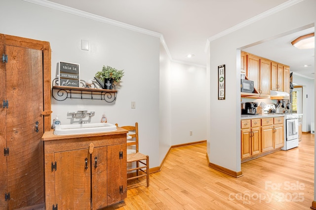 interior space featuring black microwave, a sink, white gas range oven, ornamental molding, and light wood-style flooring