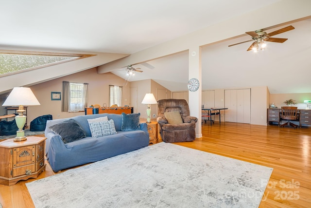living area with ceiling fan, lofted ceiling with beams, and light wood-type flooring