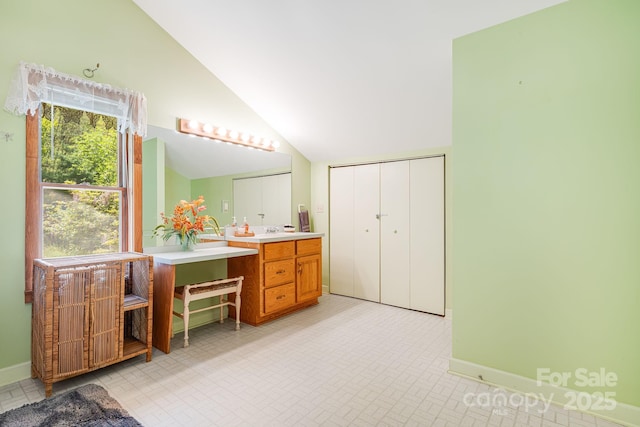 full bathroom featuring baseboards, lofted ceiling, and vanity