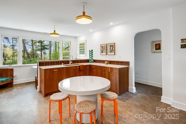 80 Sunset Dr, Marshall, NC 28753 - kitchen featuring brown cabinets, a sink, a wealth of natural light, baseboards, and arched walkways
