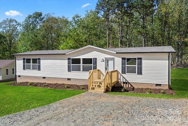 manufactured / mobile home with a shingled roof, crawl space, and a front lawn