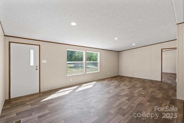 unfurnished living room with a textured ceiling, crown molding, and wood finished floors