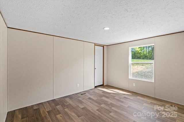 unfurnished bedroom with a closet, recessed lighting, wood finished floors, and a textured ceiling