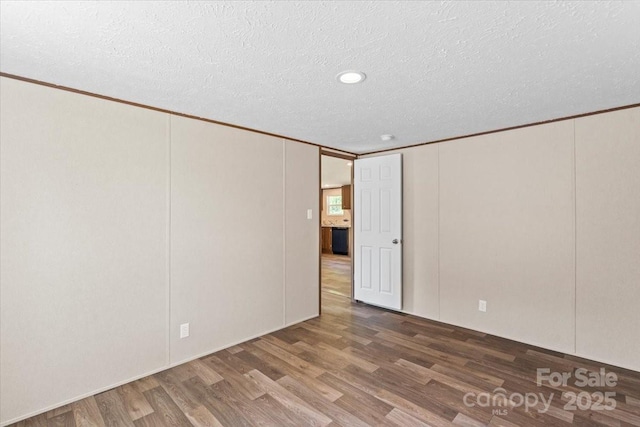 empty room with ornamental molding, wood finished floors, and a textured ceiling