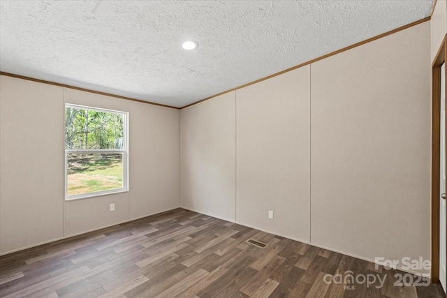 spare room with crown molding, wood finished floors, and a textured ceiling