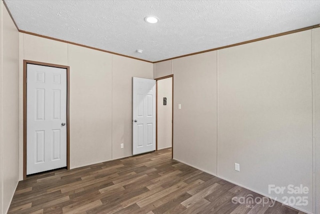 unfurnished bedroom featuring a textured ceiling, crown molding, and wood finished floors
