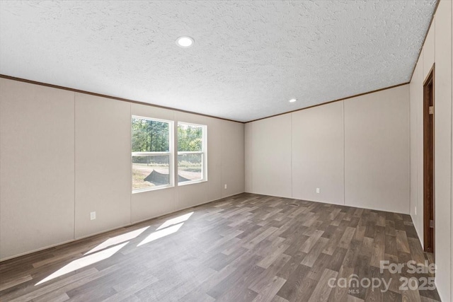 empty room featuring a decorative wall, a textured ceiling, crown molding, recessed lighting, and wood finished floors