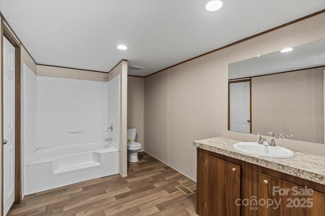 bathroom featuring toilet, a tub to relax in, recessed lighting, vanity, and wood finished floors