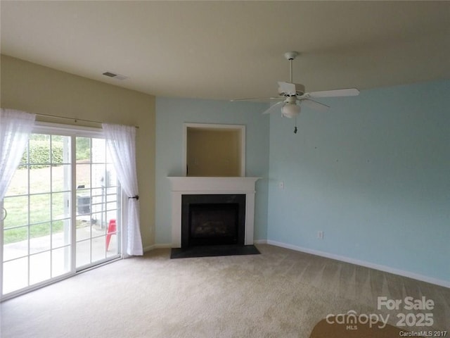 unfurnished living room with a fireplace with flush hearth, carpet flooring, baseboards, visible vents, and a ceiling fan