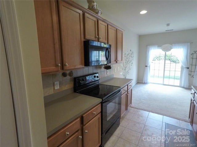 kitchen with light carpet, tasteful backsplash, black appliances, brown cabinetry, and light tile patterned floors