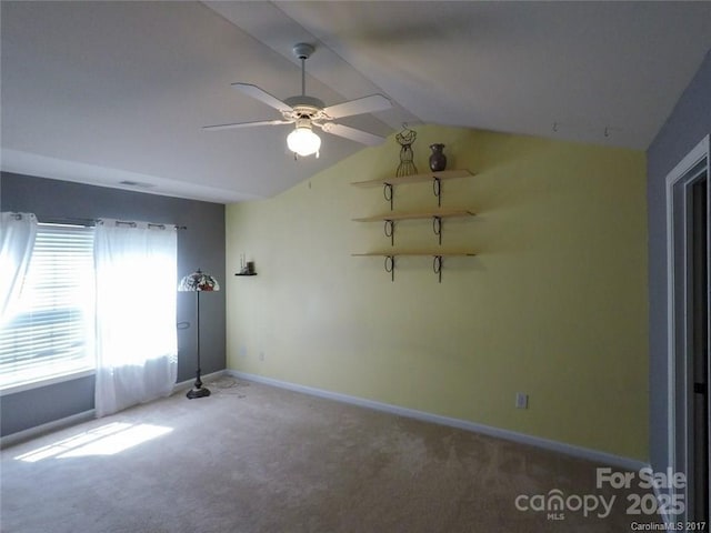 carpeted empty room featuring lofted ceiling, a ceiling fan, and baseboards